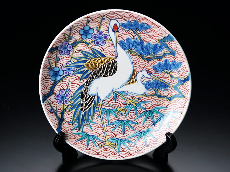 皿立てに立てた有田焼の飾り絵皿 染錦金彩・白金彩松竹梅鶴図（径19cm）