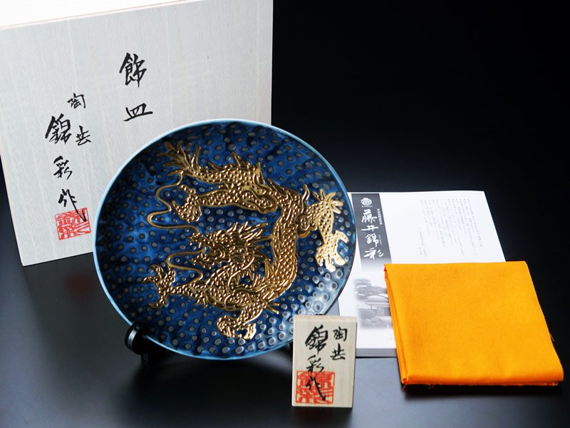 有田焼の飾り絵皿に付属する銘入りの桐箱、作品名を記した立札、ウコン布、窯元のしおり