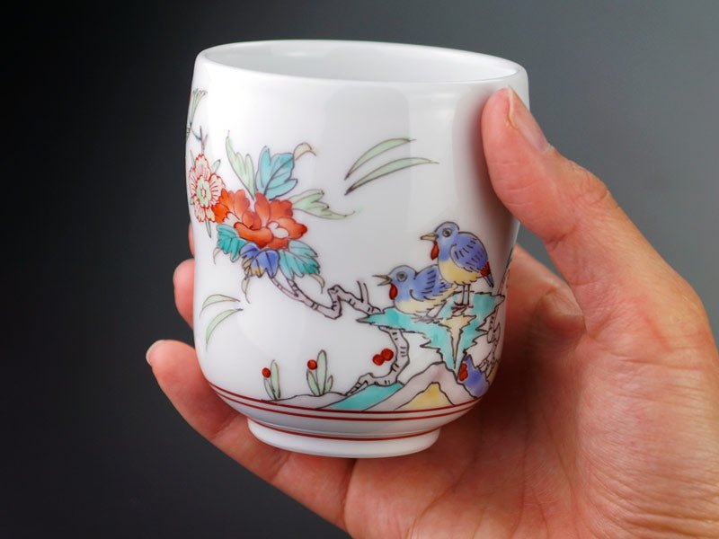 有田焼 湯呑み 色絵花鳥図。白磁に赤と青の花鳥を描いた湯呑を手に持ったところ