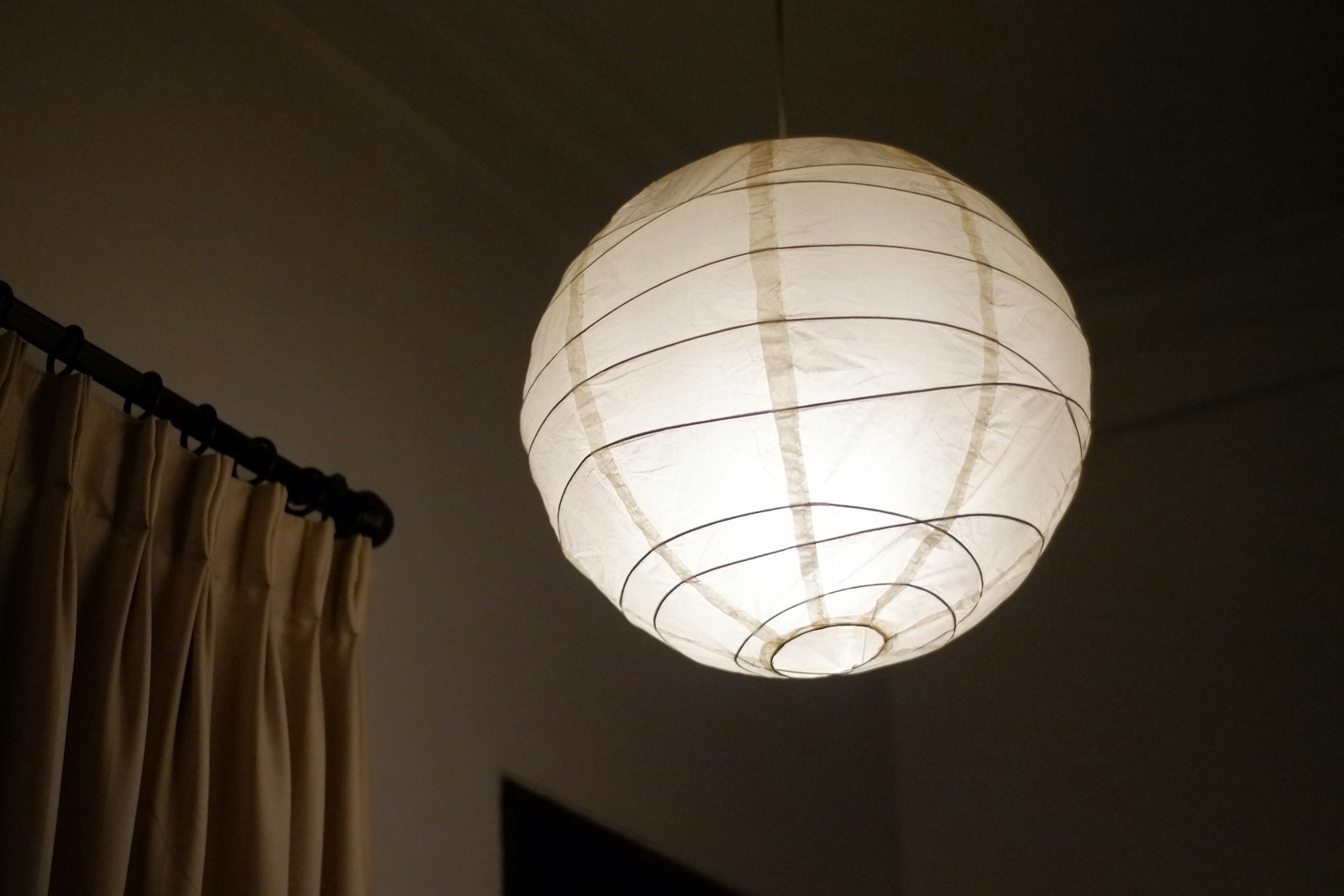 和紙を張った丸いシェードのペンダントライト。電球色で灯している