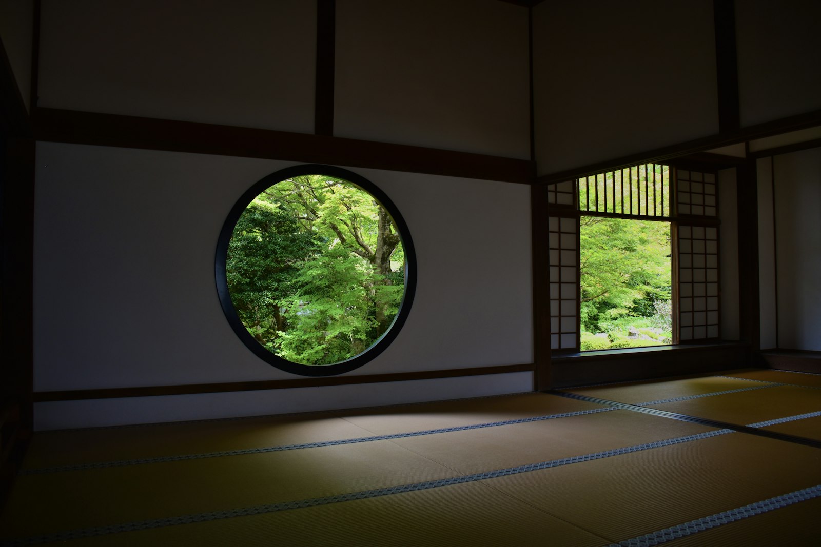 円窓から庭の緑が見える和室。畳と障子だけで整えた部屋